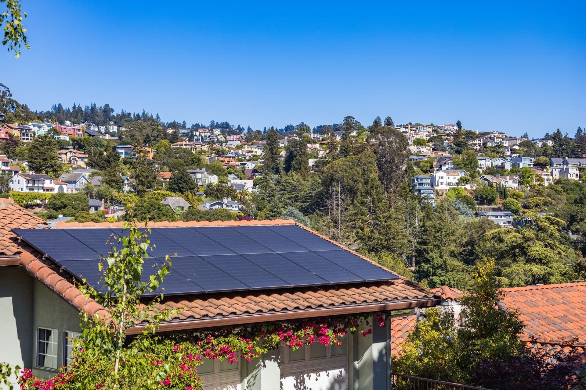 Rooftop solar array on a tiled home under a clear blue sky